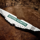 A photo of the new Aston Martin enamel badge on a brown leather surface.